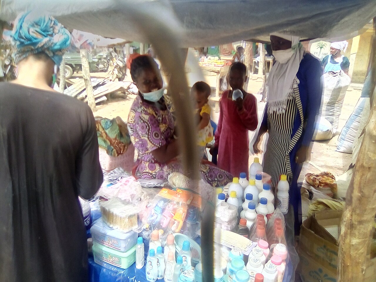A Ghanaian market trader serving customers at her stall in northern Ghana